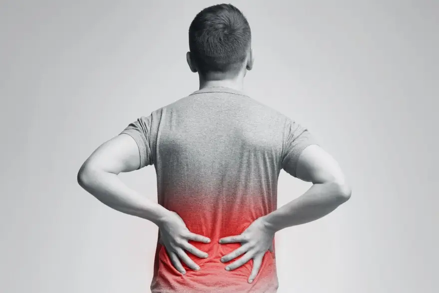 Greyscale image of a person holding their back